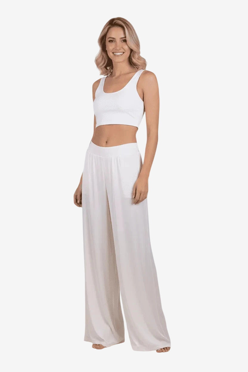Modella indossa un pantalone palazzo color avorio in viscosa effetto raso con taglio ampio.