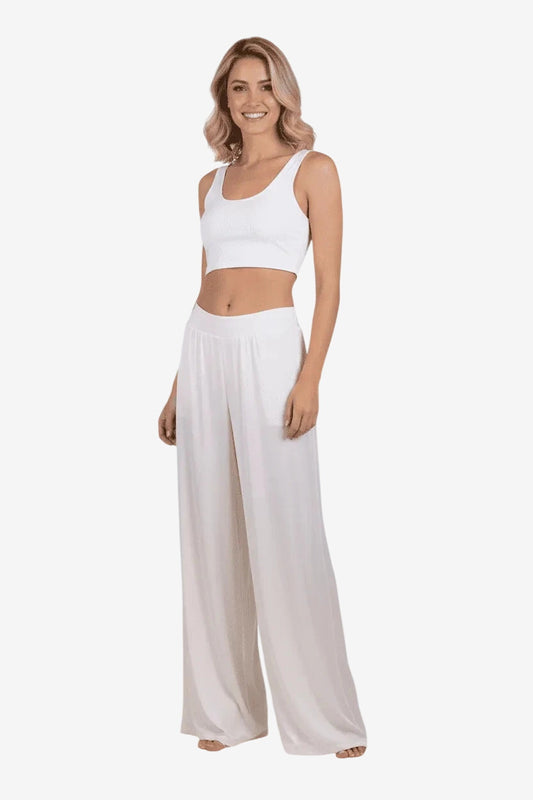 Modella indossa un pantalone palazzo color avorio in viscosa effetto raso con taglio ampio.