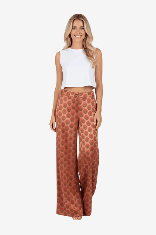 Pantalone donna a gamba larga con fantasia ruggine indossato con un top bianco.