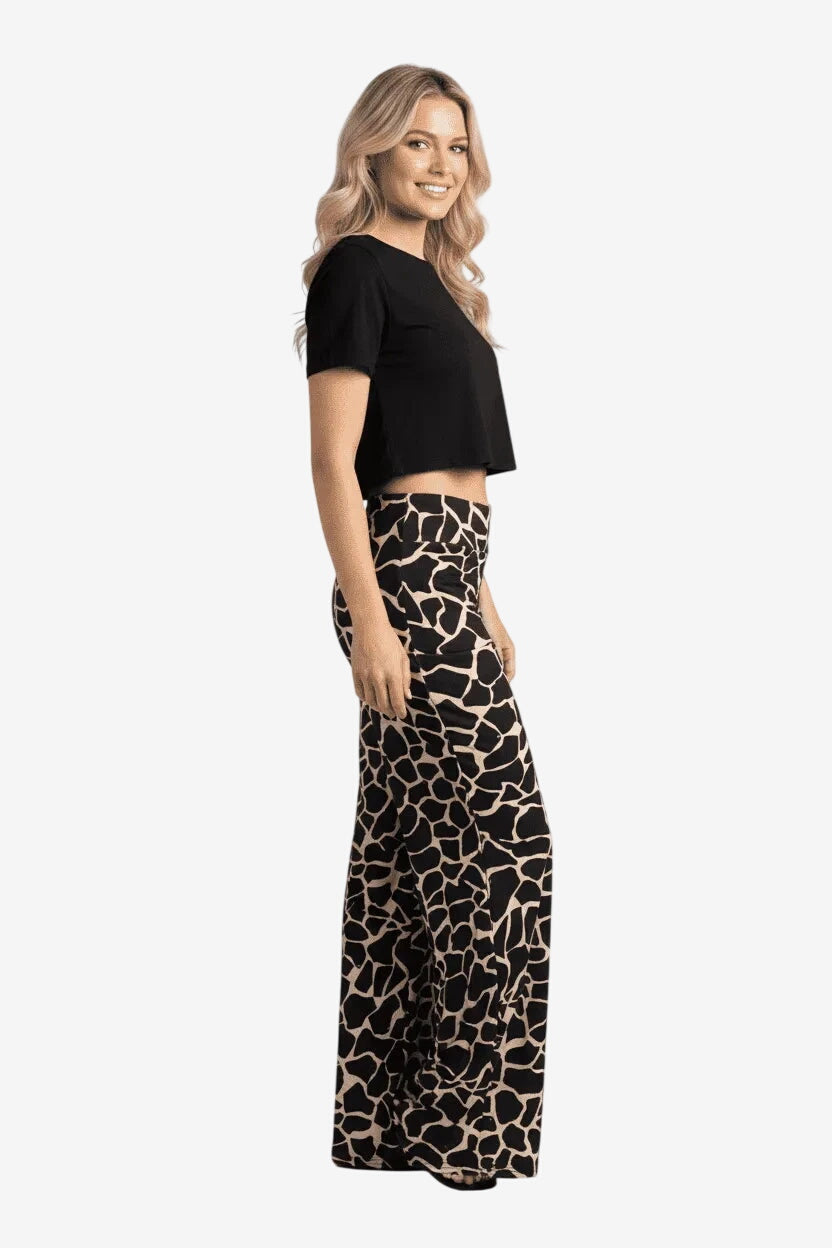 Donna che indossa pantaloni palazzo a gamba larga con stampa animalier giraffa nera e beige.