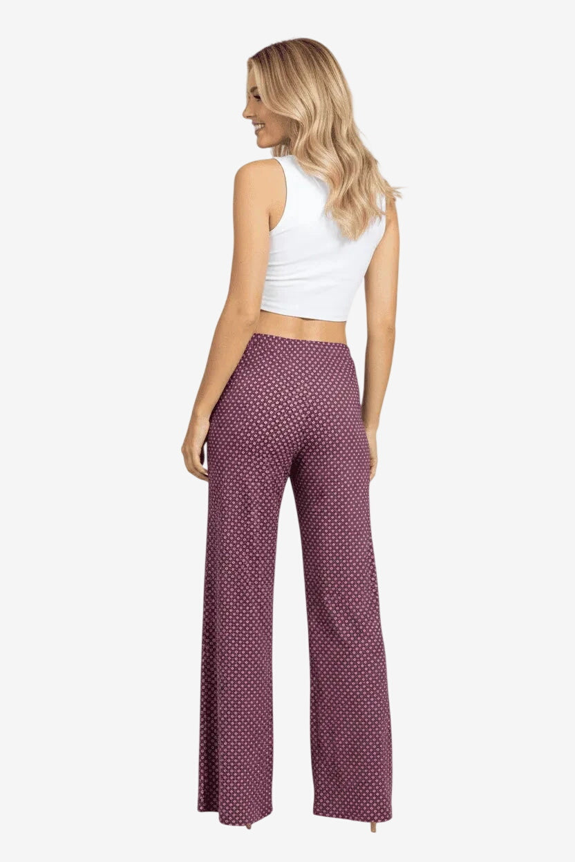 Donna che indossa un pantalone palazzo rosa con stampa geometrica e vestibilità fluida.