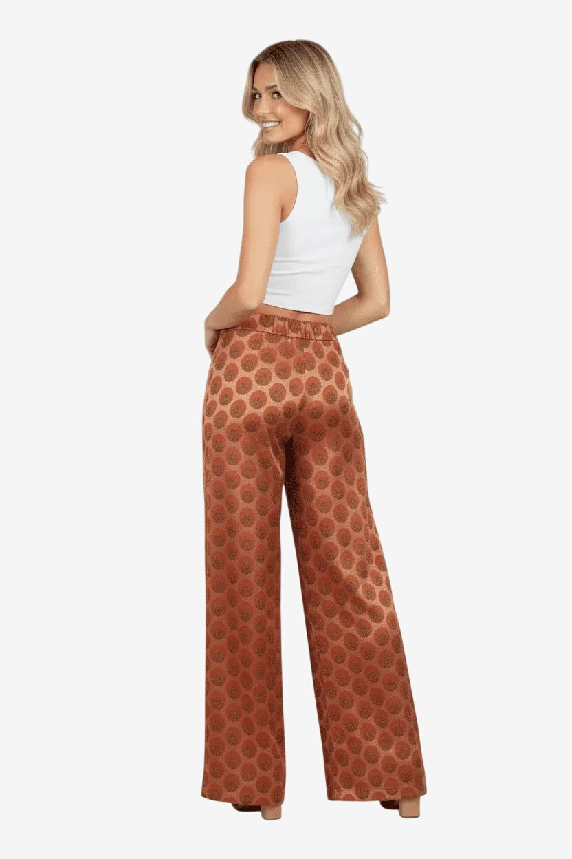 Modella di spalle indossa pantaloni a gamba larga con fantasia geometrica color ruggine.