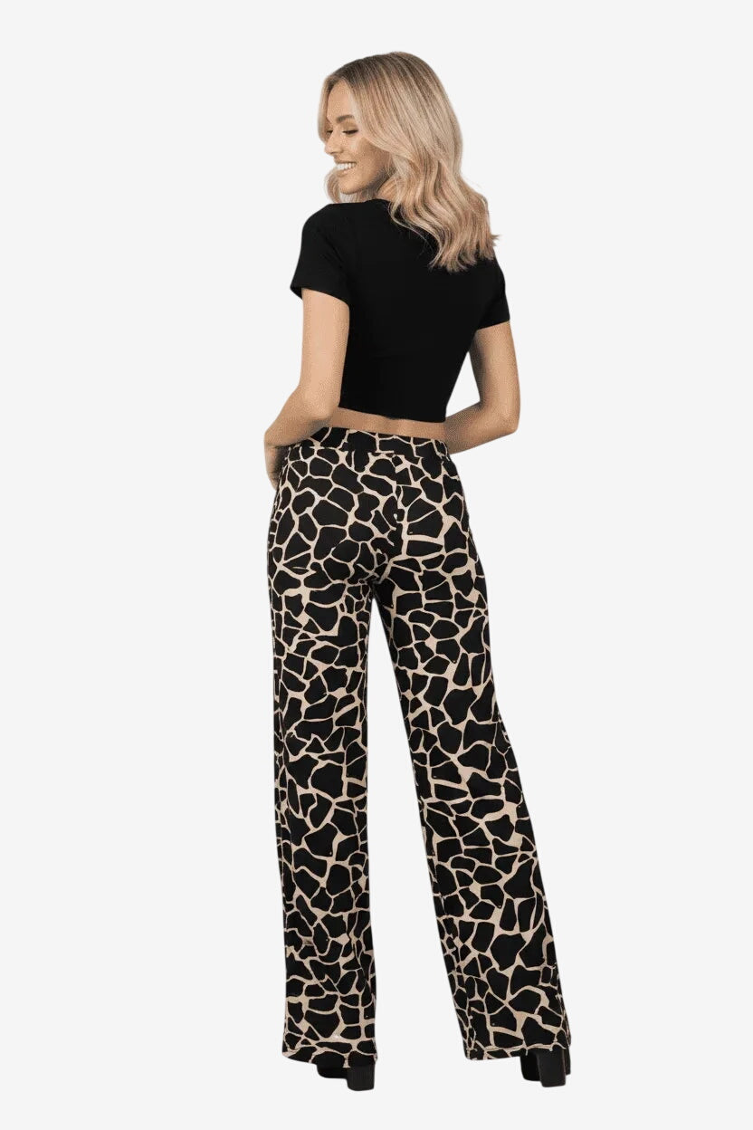 Donna che indossa pantaloni palazzo a gamba larga con stampa animalier giraffa nera e beige.