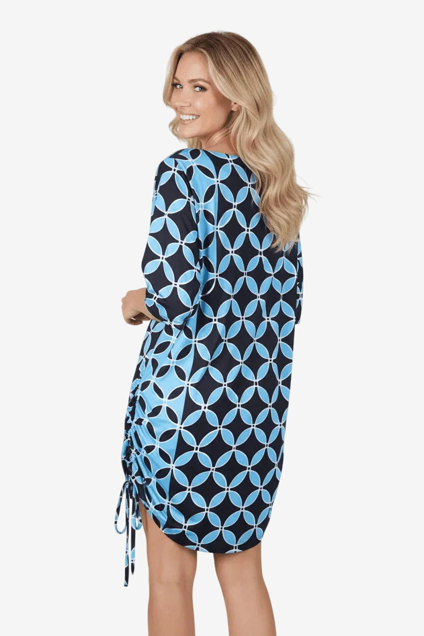 Una donna indossa un abito corto con maniche a tre quarti e una stampa geometrica blu e nera.